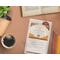 The notecard on a desk with a cup of coffee, an open book, colored pencils, and a succulent. 